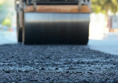 Close-up of road roller smoothing fresh asphalt on a sunny day.